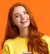 Girl searching gifts for holidays online. Carefree happy redhead female student using smartphone app, laughing joyfully, holding mobile phone, chatting or browsing social networks, orange background.